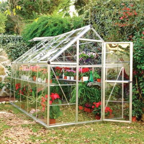 greenhouse with the door open displaying ample space for growing various plants and gardening tools.