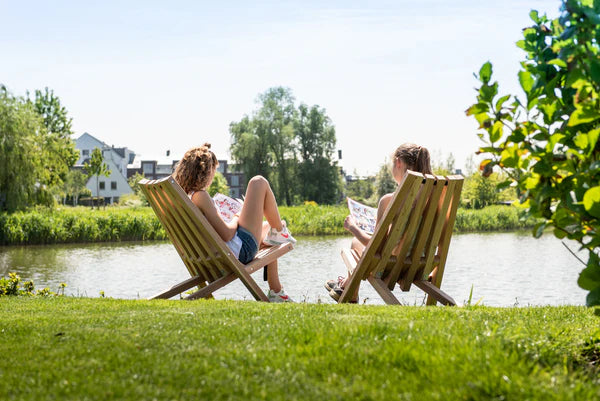  Two people relaxing on Weltevree Fieldchairs by a scenic lake, perfect for outdoor enjoyment