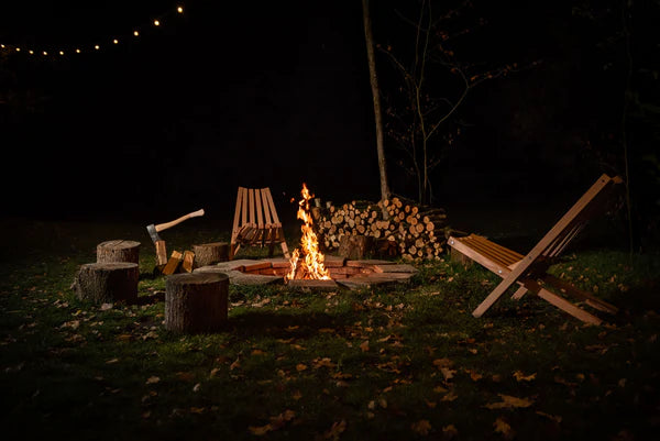 Weltevree Fieldchairs around a cozy campfire at night, ideal for outdoor gatherings.